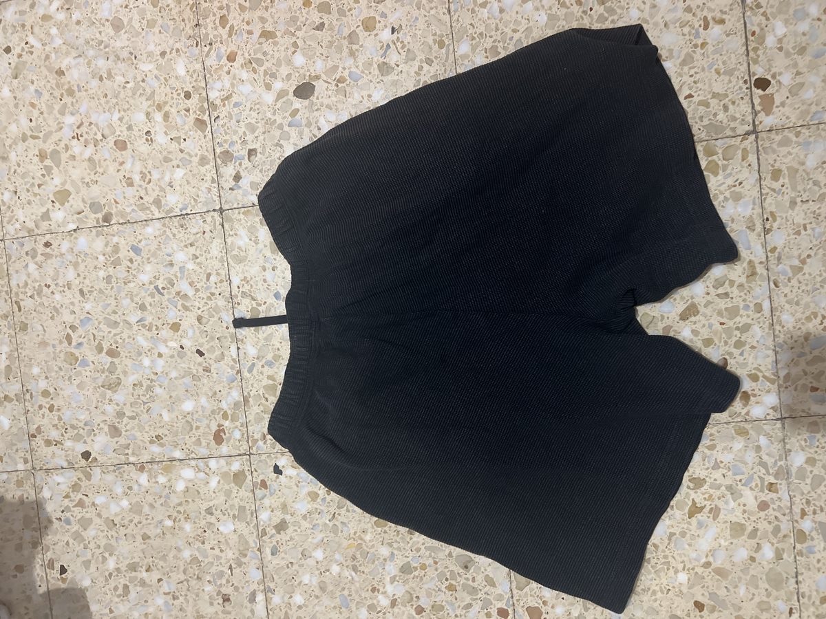 Pantalón corto negro extendido en el suelo, visto por delante