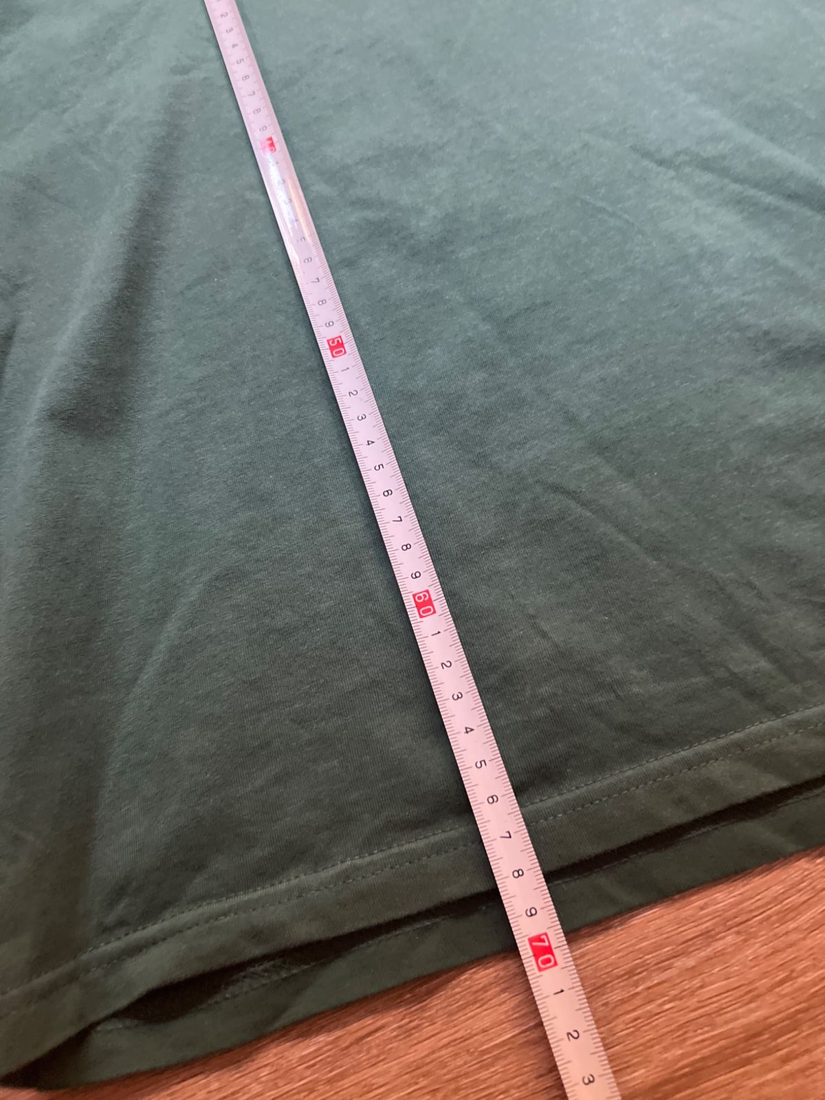 Una cinta métrica midiendo el largo de la camiseta verde Carhartt