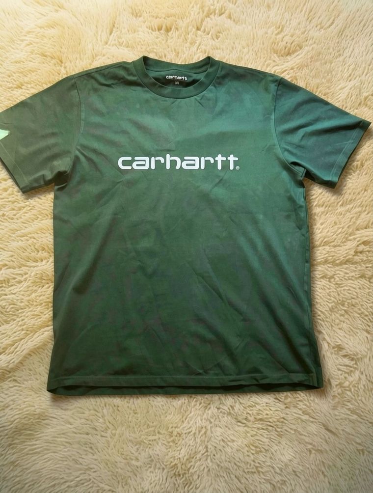 La camiseta verde sobre la alfombra clara, con una luz cálida y suave
